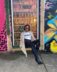 a woman sitting on a bench in front of a graffiti covered building