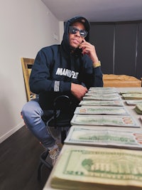 a man sitting at a table with stacks of money